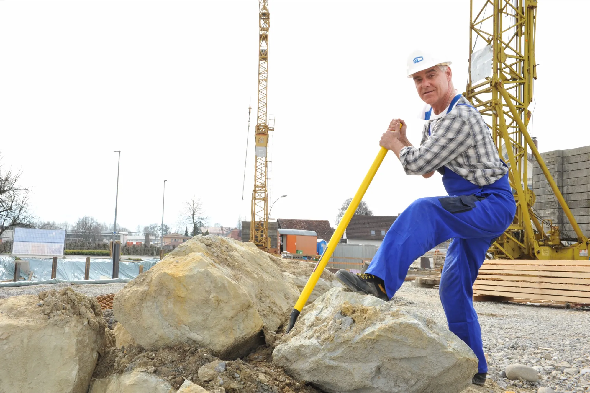 Construction worker moving a heavy stone on site with the Kuli formwork stripping bar