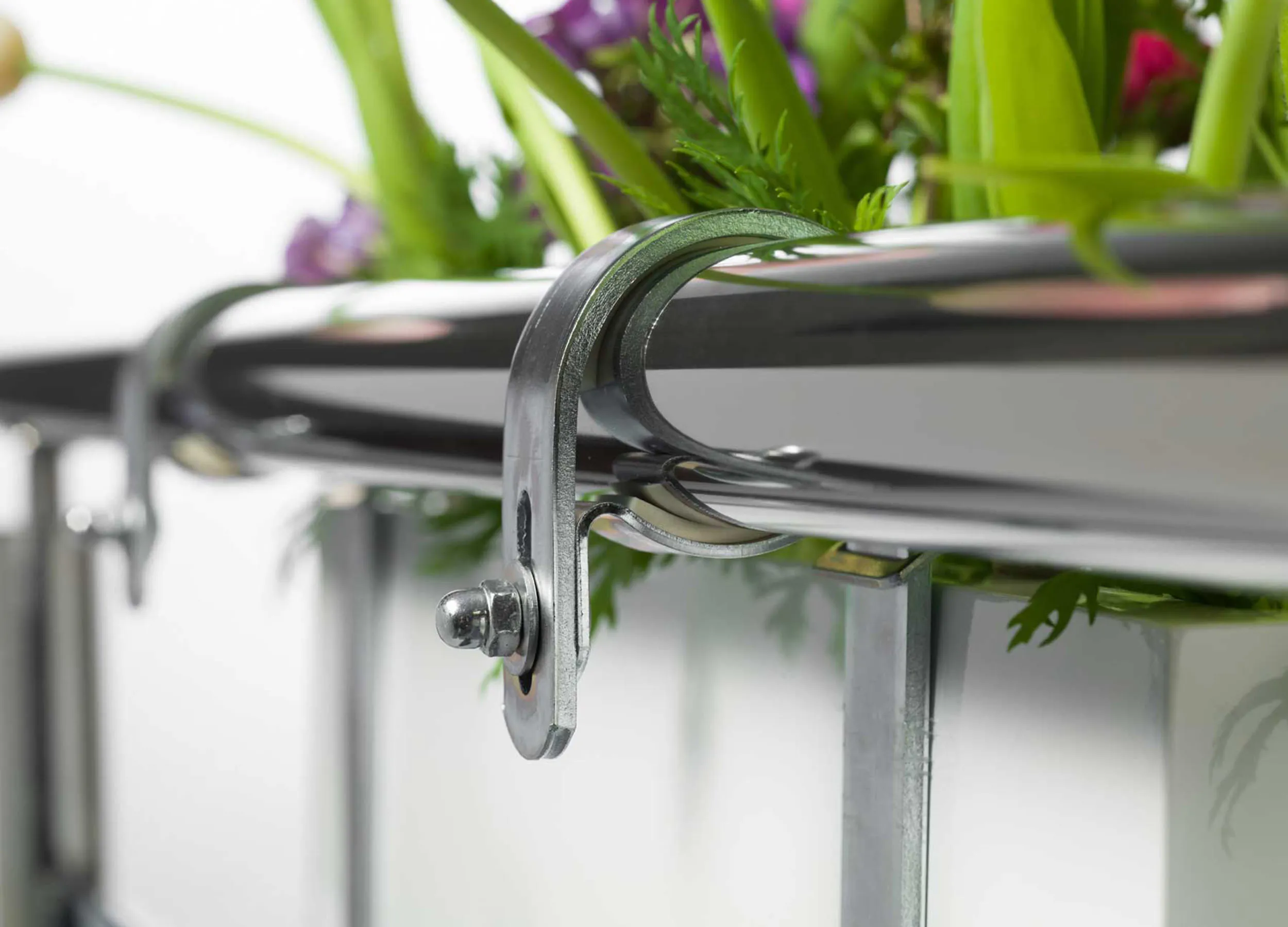 Steel flower box holder on a railing with flowering plants