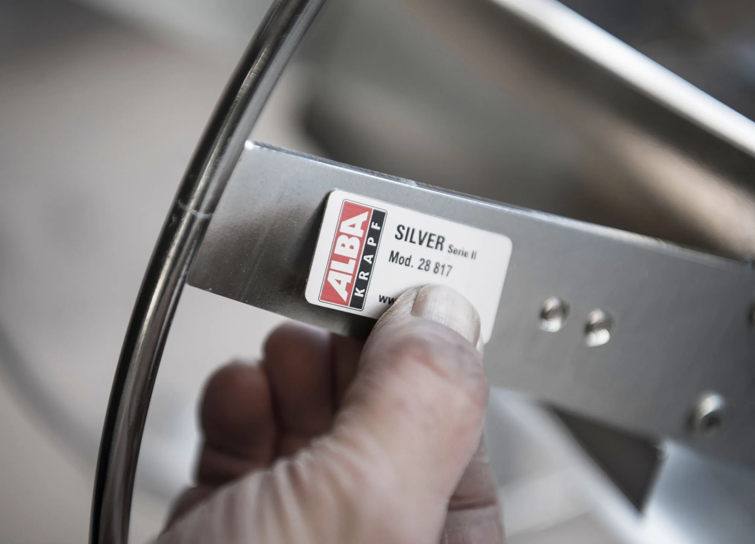 Hand on an ALBA KRAPF hose reel with SILVER nameplate — quality down to the last detail